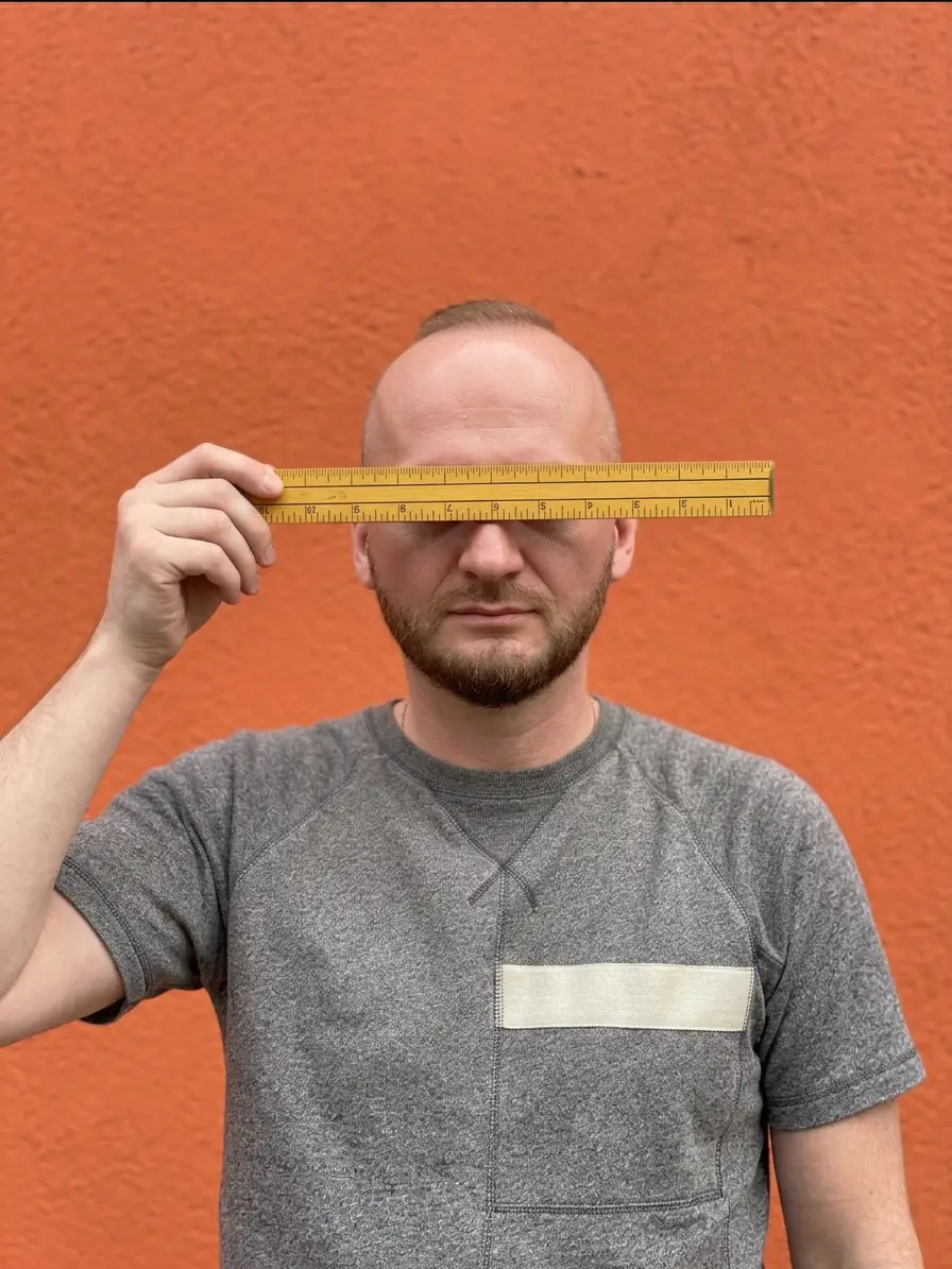 firefly gemini flash reimagine this image as me standing in front of an orange wall holding a ruler to cov 746931